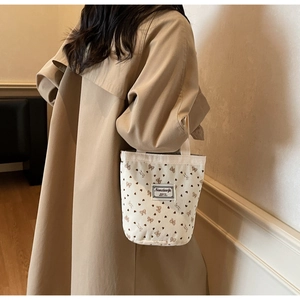 Corduroy mini tote bag with strawberry heart prints held by model in trench coat