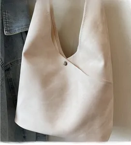 Detail of minimalist beige bucket bag with metal rivets and soft fabric texture