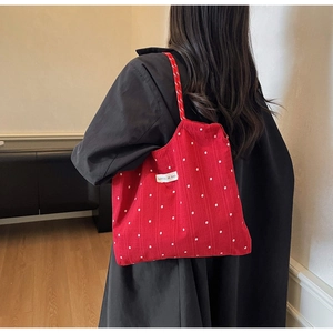 Close-up of red floral tote bag with small white flowers and branded woven label