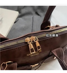 Detail of premium brown tote bag featuring golden double zipper and metal hardware