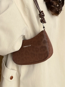 Brown leopard print shoulder bag with Creative Cat logo on a beige trench coat