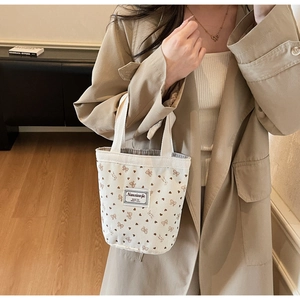 Detail of corduroy tote bag featuring brown bow prints and small heart patterns