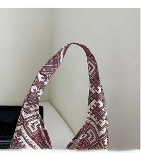 Gros plan du tissu jacquard ethnique et des coutures renforcées sur la bandoulière du sac