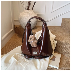 Detail view of brown faux leather hobo tote bag with plush bear charm on zipper