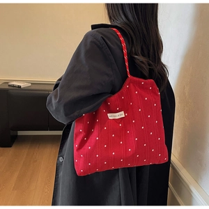 Detail of red floral tote bag with white flower pattern and rectangular label logo