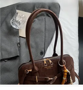 Detail of dark brown suede handbag featuring dual zippers and decorative wooden beads