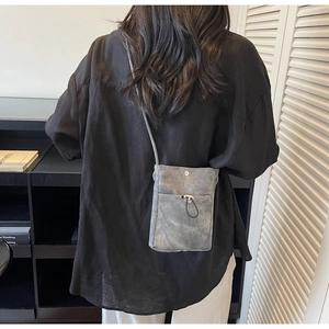 Détail d'un mini sac téléphone en toile avec texture délavée et boucle en métal