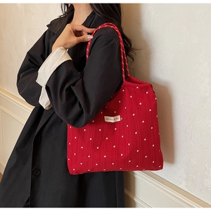 Close-up of red floral mesh tote bag featuring white flower patterns and cloth brand tag