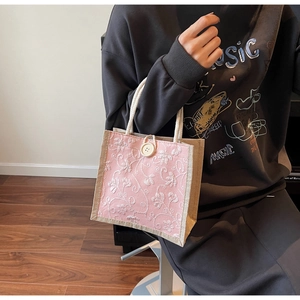 Detailed embroidery on pink linen tote bag with soft cotton rope handles and button closure