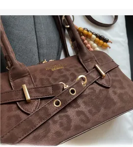 Detail of leopard print handbag showing soft suede texture and gold buckle hardware