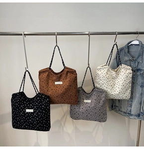 Detail of corduroy tote bags featuring heart patterns and woven straps in four colors