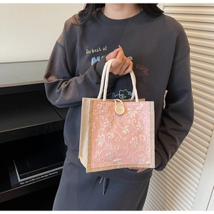 Close-up of pink linen tote with floral embroidery, hemp rope handles and large button