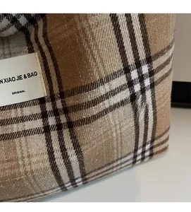 Close-up of brown checkered tote bag showing textured wool fabric and stitched brand label