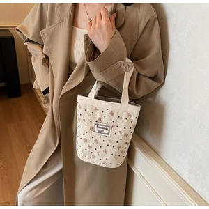 Detail of a beige corduroy tote bag featuring cute strawberry and floral heart patterns