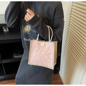Detailed view of floral embroidery on pink linen tote bag with cotton rope handle