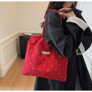 Detail of red floral chiffon tote bag with white flower patterns and woven rope handles