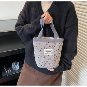 Close-up of corduroy tote bag with black bow heart patterns and woven handle