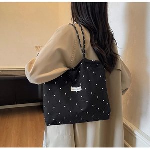 Detail of black canvas tote bag with white floral pattern and striped shoulder strap