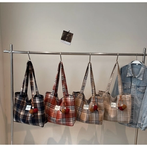 Detailed grid showing four colors of plaid tote bags with plush ball charms on a rack