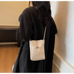 Gros plan détaillé d'un sac de téléphone en toile blanc crème avec cordon sur un manteau noir