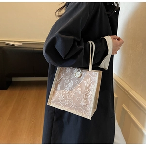 Detailed close-up of linen tote bag with white floral embroidery and woven rope handle
