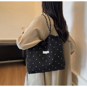 Model wearing a large floral mesh tote bag with a khaki coat in a minimalist setting