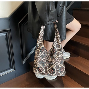 Sac cabas ethnique à motifs géométriques porté par un mannequin dans un escalier en bois