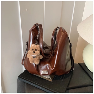 Deep brown glossy patent leather shoulder bag with a cute plush bear pendant accessory