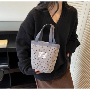 Close-up of grey corduroy tote bag featuring black heart patterns and sturdy handles