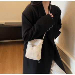 Détail d'un sac à bandoulière beige minimaliste avec cordon décoratif et bouton pression
