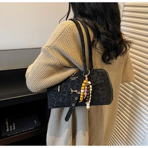 Detail of black leopard print crossbody bag with vintage wooden beaded charm and matte texture