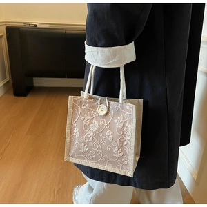 Detail of jute mini tote bag featuring white floral embroidery and cotton rope handles