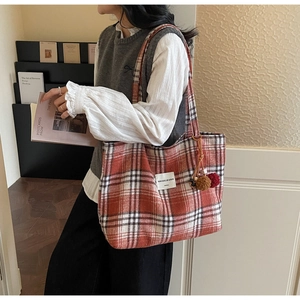 Detail of red and white checkered tote bag with plush pom-pom and shoulder strap