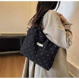 Detail of black canvas tote bag with floral pattern and brand label on shoulder