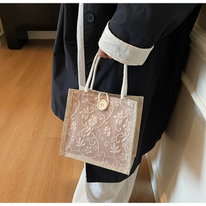 Close-up of vintage linen tote with white floral embroidery and hemp rope handles