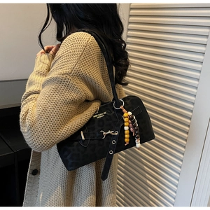 Close-up of black retro shoulder bag with leopard pattern texture and colorful bead charm