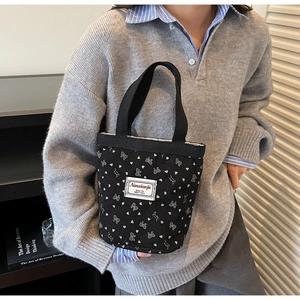 Detail of black corduroy tote bag with heart patterns and white woven brand label