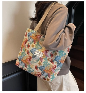 Detail of colorful floral jacquard tote bag with beige straps worn over the shoulder