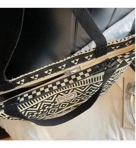 Close-up of smooth silver metal zipper on black and white geometric canvas tote bag