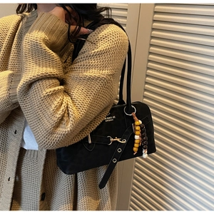 Detail of black vintage crossbody bag with beaded pendant and gold buckle on a model
