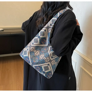 Détail d'un grand sac cabas en maille ethnique aux motifs géométriques porté par un mannequin