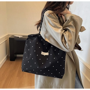 Detail of black floral canvas tote bag with Nan Xiao Jie brand label and long shoulder straps