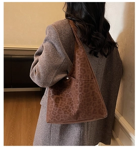 Detail of warm brown leopard print suede tote bag with metallic buckle accent