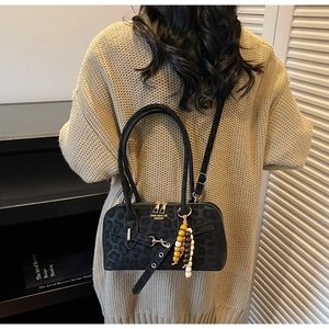 Detail of black leopard print crossbody bag with colorful beaded charm and metal buckle