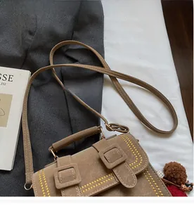 Detail der vintage braunen Umhängetasche aus Leder mit gelben Nähten und oberem Handgriff