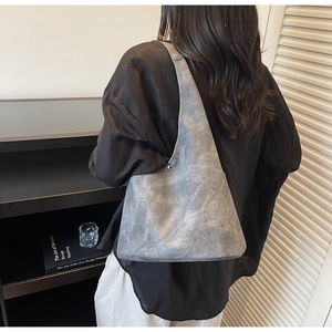 Detailed back view of a minimalist grey suede shoulder bag shown on a model