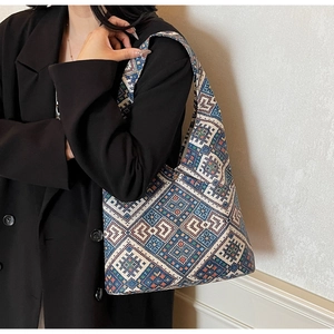 Détail des motifs ethniques géométriques sur un sac cabas tissé porté par un mannequin