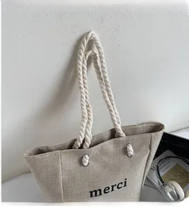 Detail of linen tote bag featuring cotton rope handles and printed merci text logo
