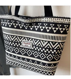Detail of canvas tote bag with black and white geometric pattern and woven handles