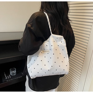 Close-up of white canvas tote bag featuring black floral patterns and striped shoulder strap